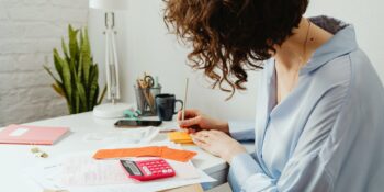 Une femme à son bureau calcule et écrit.