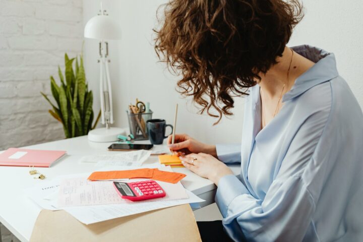 Une femme à son bureau calcule et écrit.