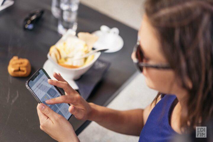 Une femme consulte son espace client EDIFIM sur son téléphone.