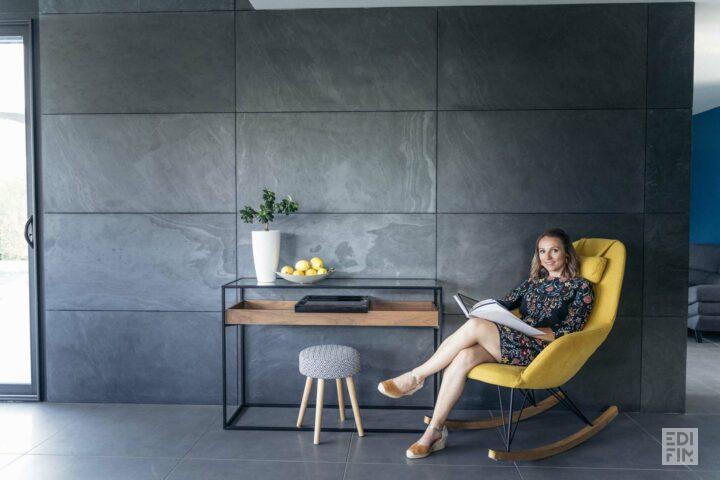 Une femme assise dans un fauteuil lit un livre.